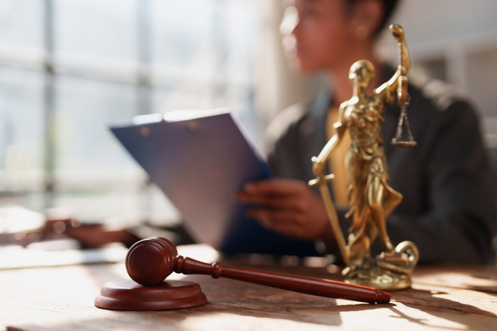 Image of a female lawyer in the background and a gavel and figurine of Lady Justice on her desk in the foreground. Indicates court expectations after a bail bond has been issued